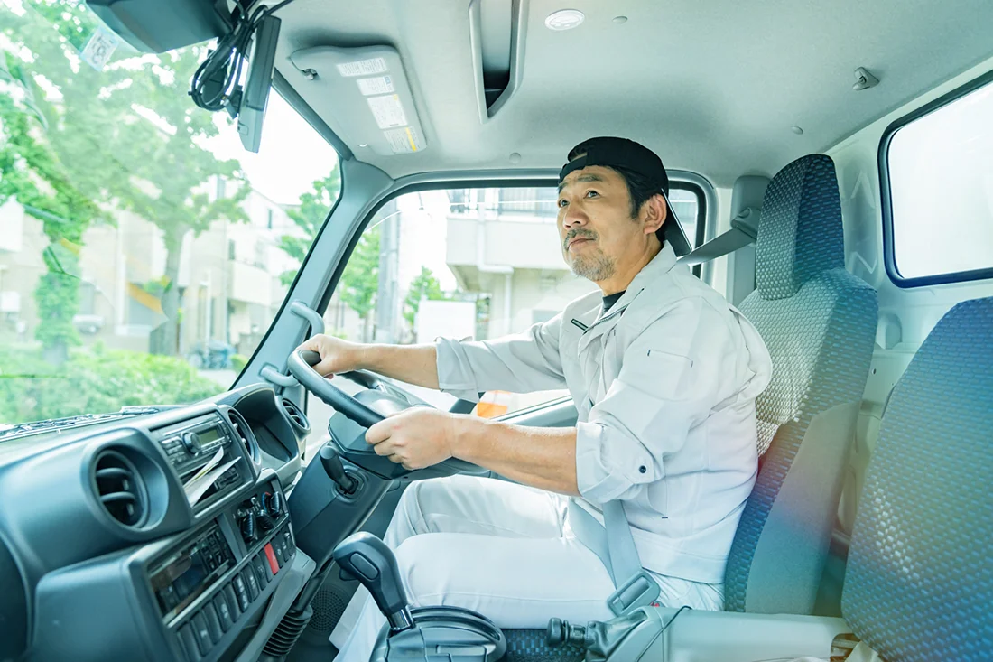 運転席で安全運転をする建築会社の作業員男性